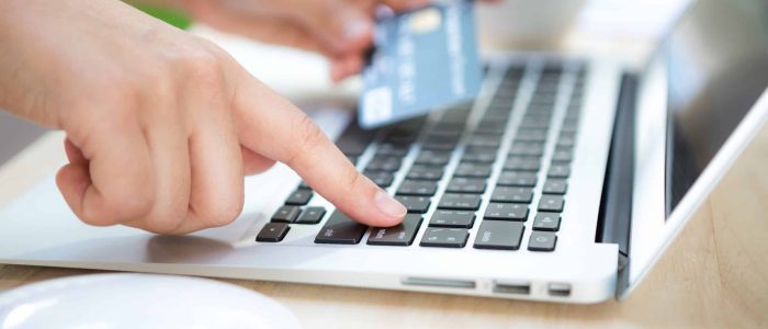 Hands holding a credit card and using laptop computer for online shopping